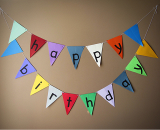 Multi-coloured happy birthday bunting hanging ona wall